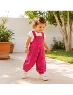 Niña caminando al aire libre con peto rosa de rayas de Pachamama Kids.